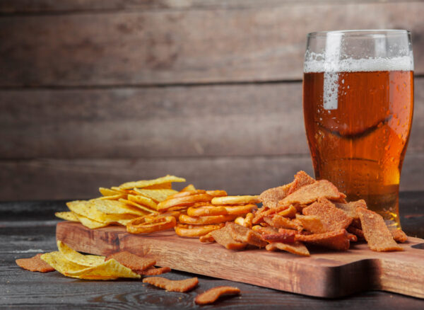 Lager beer and snacks on wooden table. Nuts, chips, pretzel