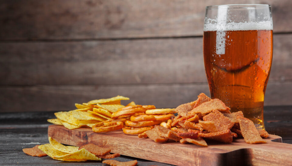 Lager beer and snacks on wooden table. Nuts, chips, pretzel